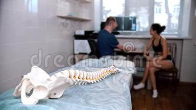 脊椎治疗-医生在手术前检查年轻妇女-放置在人体脊柱上的模型